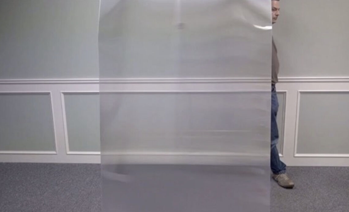 Un homme quasi invisible en passant derrière une plaque transparente