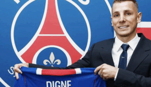Luca Digne, devant l'emblème du club de football, un maillot à la main